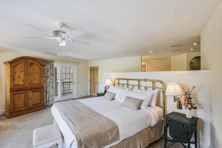 Relax in your spacious primary suite with vaulted ceilings, elegant furnishings, and French doors leading to your private outdoor space—a serene retreat for restful nights.