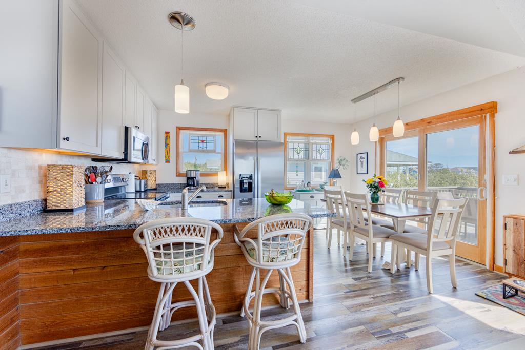 Your sun-filled kitchen and dining area blends coastal style with modern appliances, inviting you to gather at the breakfast bar or enjoy meals with a view.