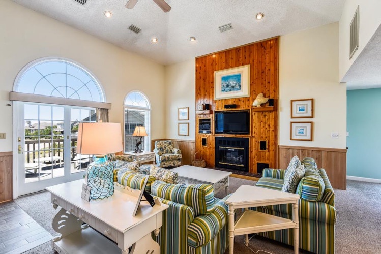 Unwind in your bright, airy living space where vaulted ceilings and warm coastal décor invite you to relax, while large arched doors open to your private balcony with views beyond.