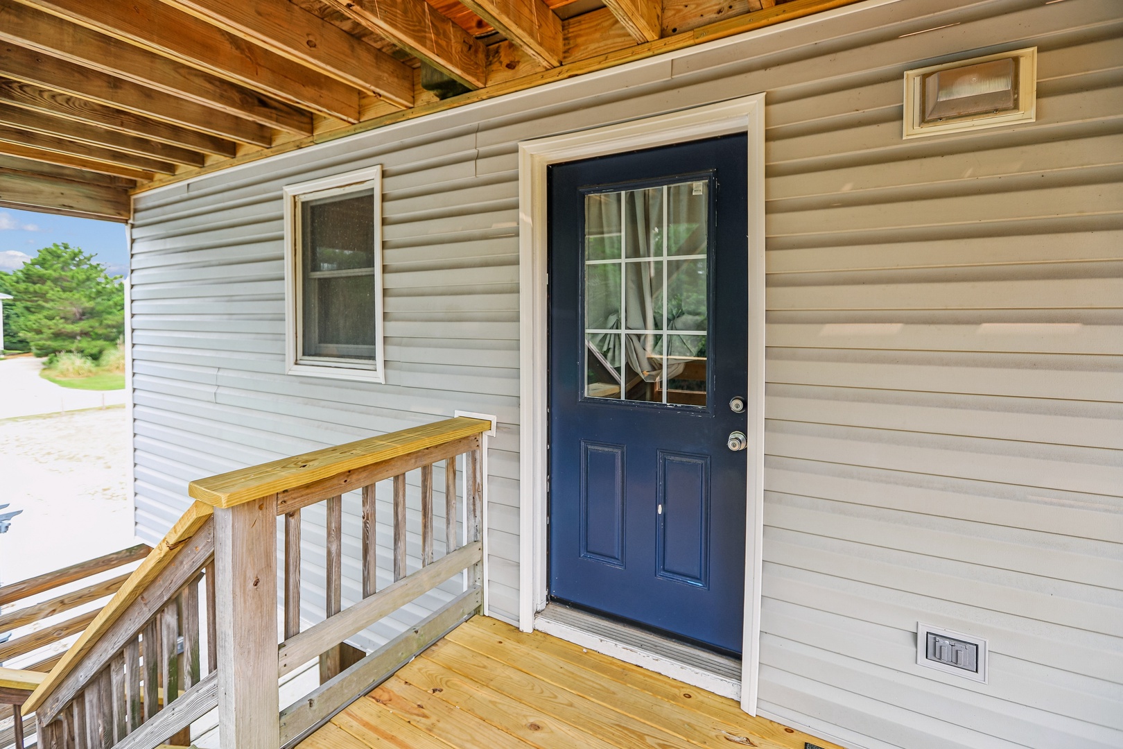 The entrance welcomes you with fresh wood details and peaceful, tree-lined surroundings—your getaway starts here.