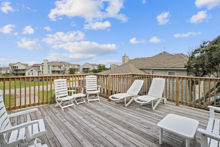 Unwind on your private deck with a peaceful neighborhood view. White loungers and chairs offer the perfect spot to soak up the sun and relax outdoors.