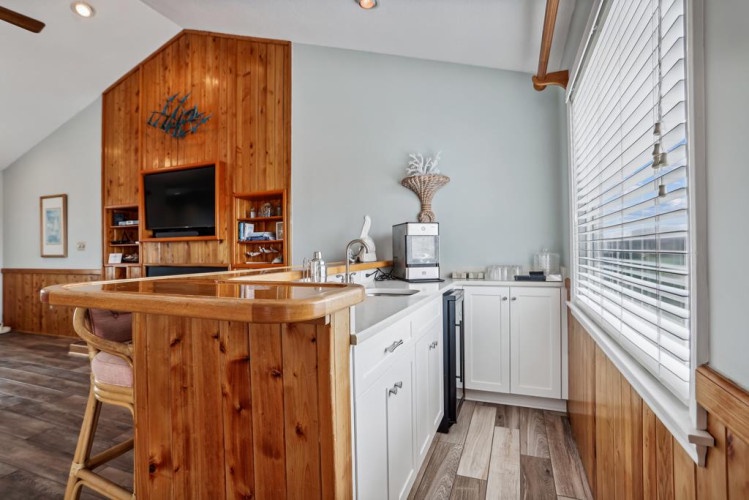 Relax in your bright open-plan retreat where warm wood tones blend with modern comforts. Sunlight floods the space through large windows while you prepare meals at the island or unwind with entertainment.