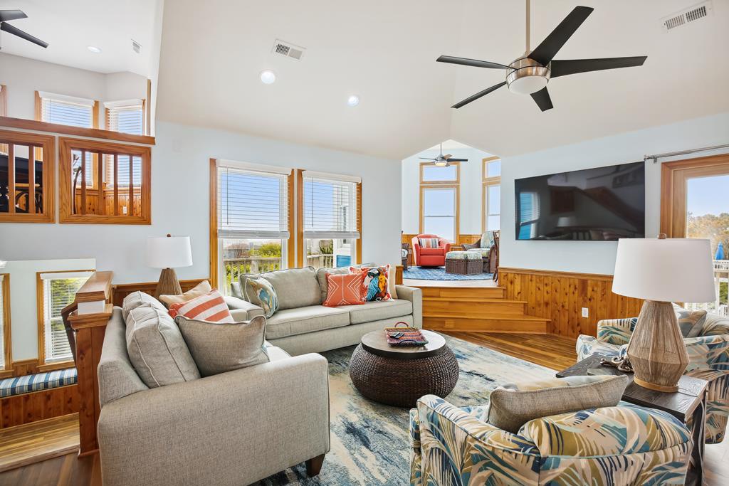 Sink into plush seating in your sunlit living room, where cathedral ceilings and warm wood tones create a breezy coastal retreat. Gather with loved ones as natural light pours through oversized windows.