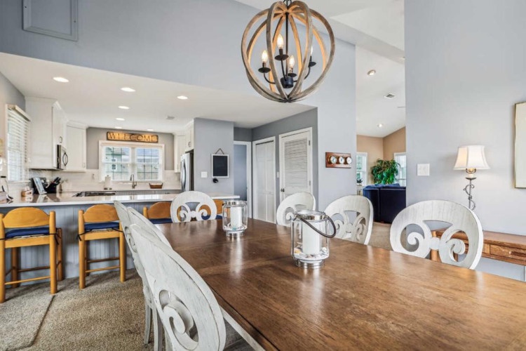 Picture yourself enjoying meals at this welcoming dining table, where the charming overhead chandelier sets a cozy mood. Just steps away, your fully equipped kitchen awaits, ready for your culinary adventures.