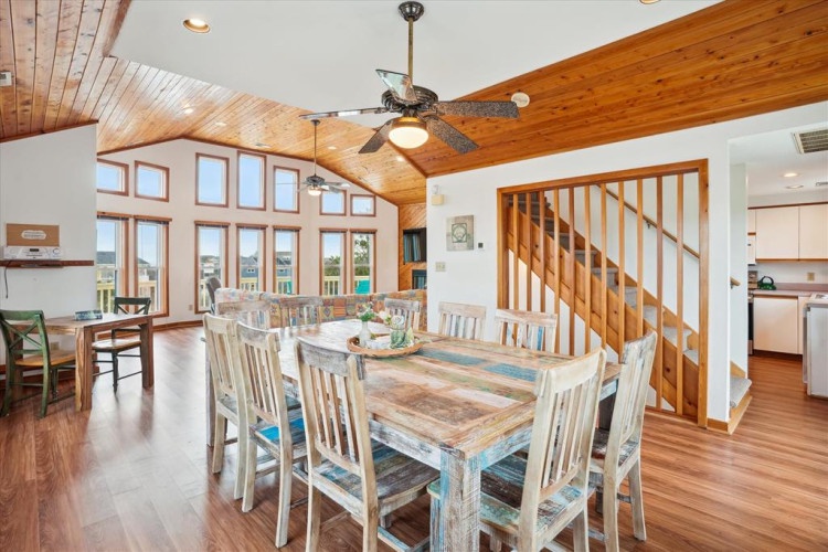 Gather around the spacious dining table, where sunlight streams through tall windows and a ceiling fan keeps you comfortable. Perfect for family meals or game nights in your coastal retreat.