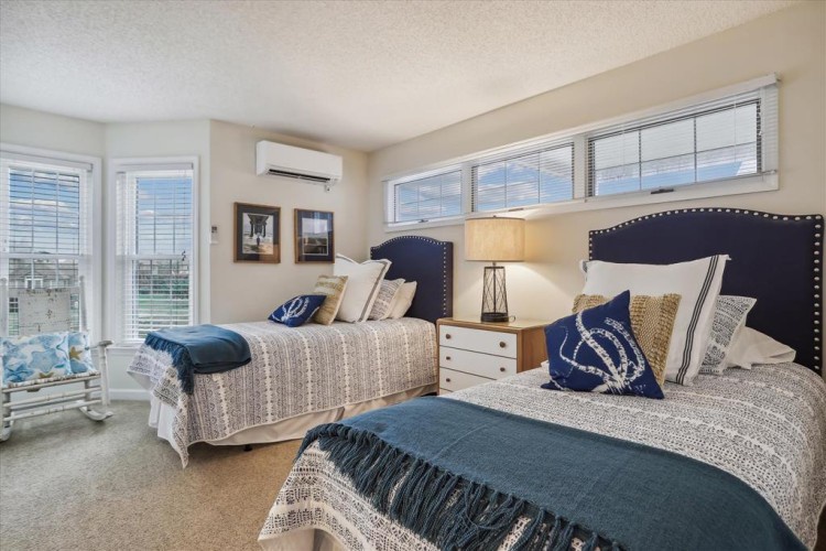 Relax in this bright bedroom with two comfortable beds, coastal-inspired décor, and modern air conditioning for your perfect night's rest.