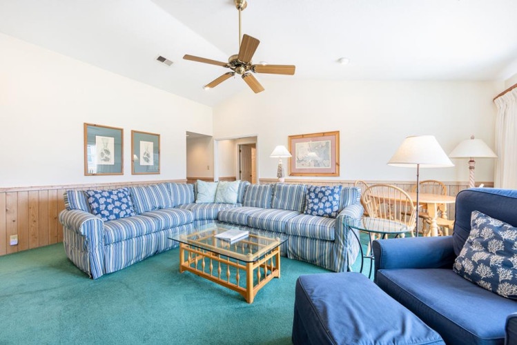 Relax in your spacious living room with comfortable striped sofas, coastal decor, and a ceiling fan to keep you cool during your stay.