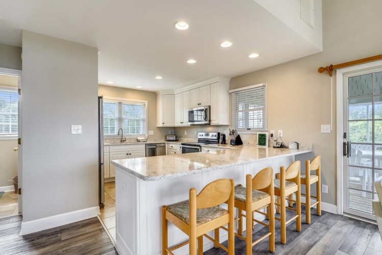 Your bright, spacious kitchen features granite countertops, stainless steel appliances, and bar seating for casual dining. Sunlight streams through plantation shutters, creating a welcoming space to prepare and enjoy your meals together.