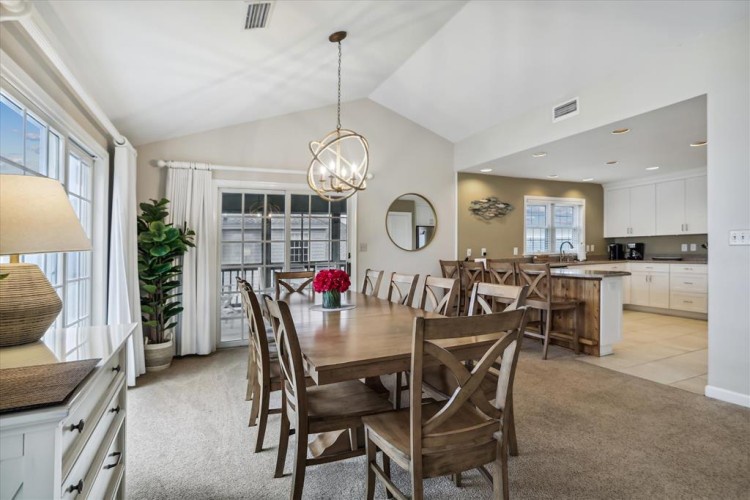 Your open-concept dining and kitchen space welcomes you with vaulted ceilings, a striking modern chandelier, and warm natural light streaming through sliding glass doors. Perfect for shared meals and easy entertaining.