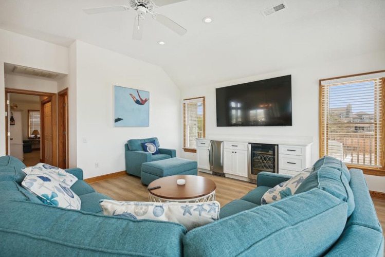 Sink into plush turquoise seating as you unwind in your bright, coastal-inspired living room with vaulted ceilings, a large TV, and a chilled beverage center at your fingertips.