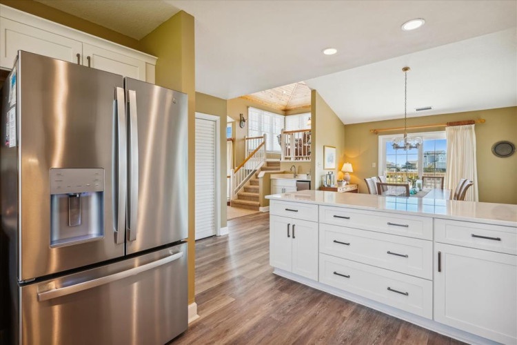 Step into your open-plan retreat where a modern kitchen flows seamlessly into bright living spaces. Vaulted ceilings and warm natural light create an inviting atmosphere for your vacation stay.