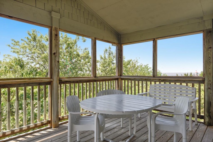 Settle into your private screened porch where fresh air meets comfort. Sip morning coffee at this serene outdoor dining spot framed by lush treetops and peaceful countryside.