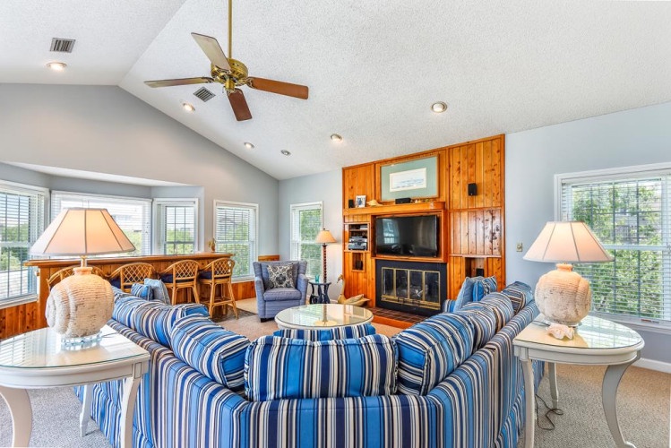 Relax in your bright, welcoming living room with vaulted ceilings, cozy seating, and a warm fireplace—perfect for gathering after beach days or evening wind-downs.