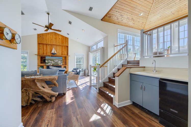 Light-filled living room invites you to unwind under vaulted wood ceilings, with airy windows framing scenic views and a cozy open layout perfect for your getaway.