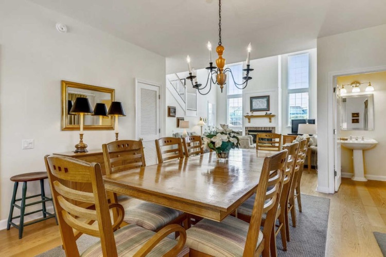 Gather around this warm, inviting dining table where you can share meals and make memories with your group. Natural light pours in from tall windows, creating the perfect atmosphere for your vacation meals.