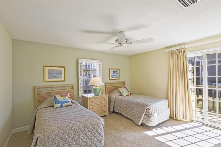 This sunny bedroom features two cozy beds, perfect for family or friends, with soft linens and a ceiling fan to keep you comfortable. Step outside through the French doors to your private outdoor retreat.
