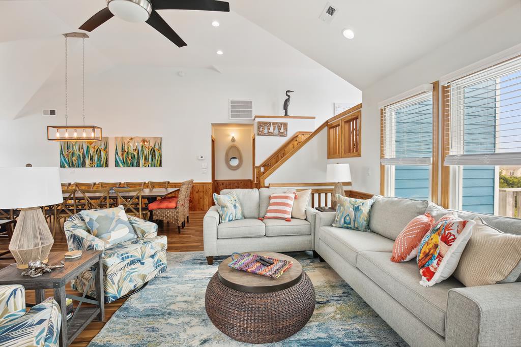 Relax in your spacious living area with soaring vaulted ceilings, coastal-inspired décor, and abundant natural light pouring through large windows, creating the perfect coastal retreat ambiance.