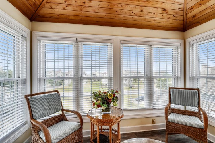 Settle into your peaceful sunroom retreat, where natural light streams through expansive windows and a cozy seating area invites you to unwind with views of the surrounding landscape.