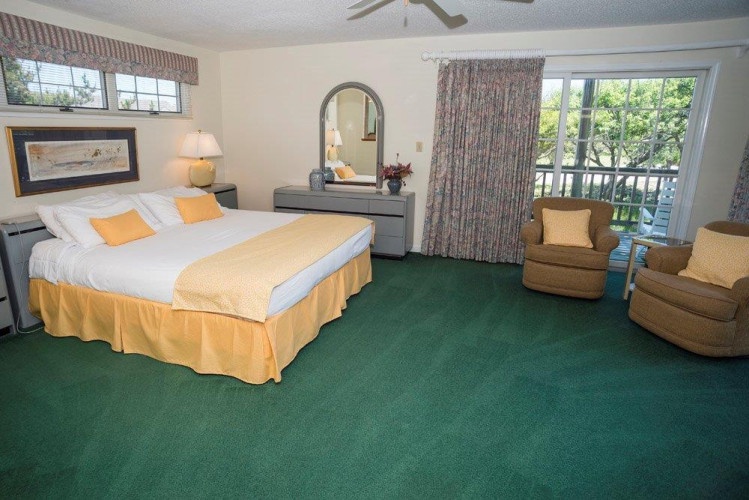 Your bright retreat features a plush bed with cheerful accents, cozy seating, and sliding doors opening to a private balcony with leafy views—perfect for morning coffee or unwinding.
