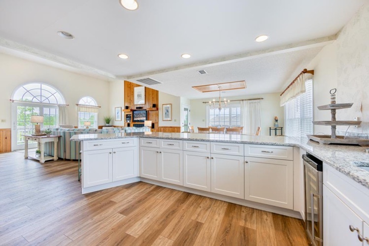 Spacious open-concept living where gleaming granite counters, white cabinetry, and warm wood floors invite you to gather, cook, and relax—all bathed in natural light from the arched windows overlooking the outdoors.
