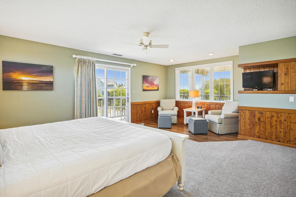 Unwind in your spacious master suite, where warm wood paneling meets coastal charm. Relax on the cozy seating area or step onto your private balcony to soak in refreshing breezes and sunlit views.