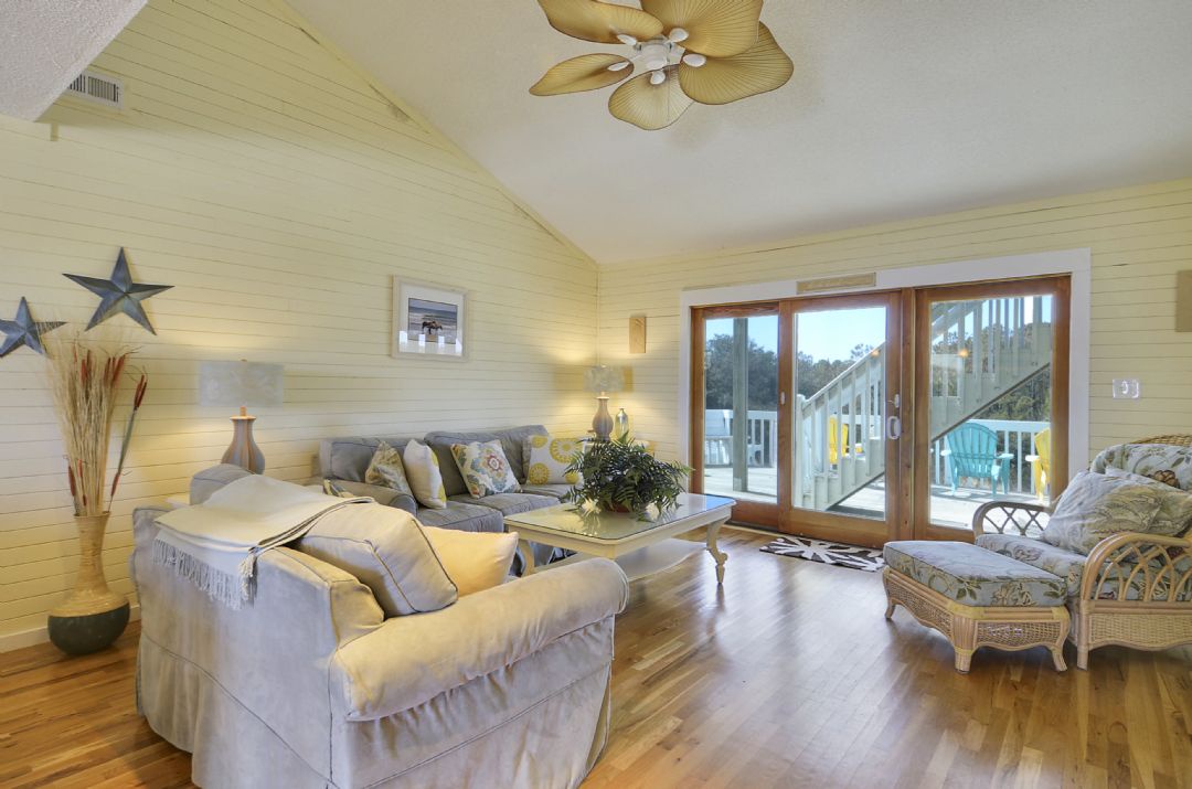 Sink into plush sofas in your light-filled living room, where coastal charm meets comfort. Natural wood floors and breezy décor invite you to unwind before stepping out to the deck.