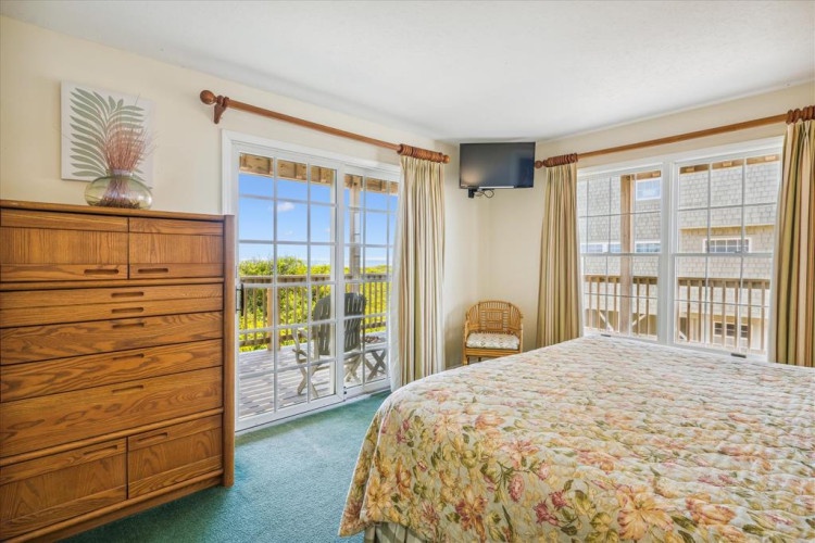 Wake up to sweeping coastal views from your bedroom, where bright windows frame the greenery and ocean beyond—your own peaceful retreat awaits.