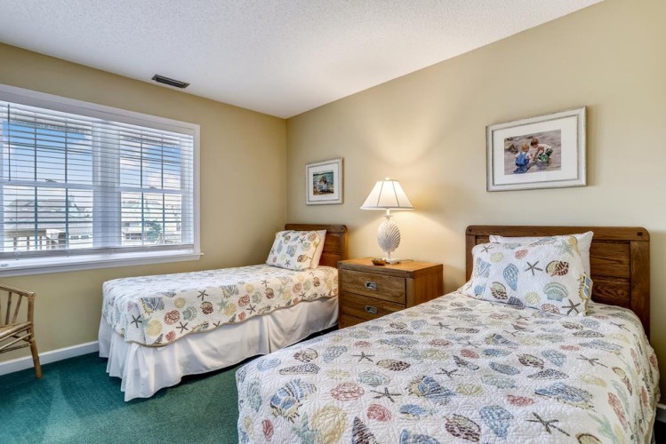 Two cozy twin beds with charming seashell bedding invite restful nights, while the sunny window fills your room with natural light and coastal warmth.