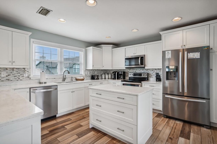 Your spacious kitchen welcomes with gleaming stainless appliances, white cabinetry, and warm wood floors—perfect for preparing meals and gathering together.