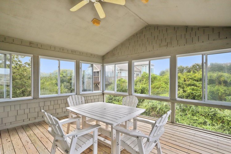 Your private screened-in porch offers a peaceful retreat surrounded by lush treetops, with a dining table perfect for morning coffee or evening meals in the fresh air.