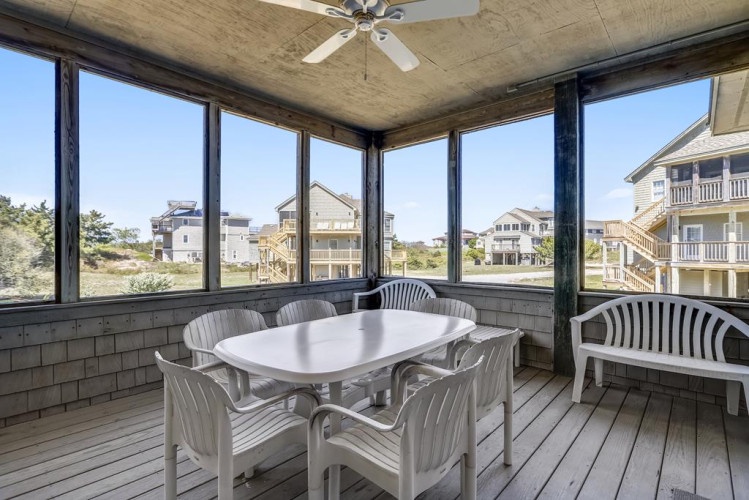 Enjoy your morning coffee or evening meals in this breezy screened porch, where coastal breezes and neighborhood views create the perfect backdrop for relaxation.