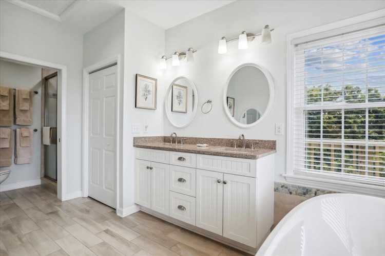 Your elegant dual-vanity bathroom features stylish round mirrors, warm lighting, and a serene view through plantation shutters—perfect for unwinding after a day of adventure.