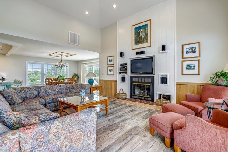 Settle into your spacious living area with soaring ceilings, a cozy fireplace, and natural light streaming through large windows. The open layout connects you to the dining space, perfect for gathering and unwinding.