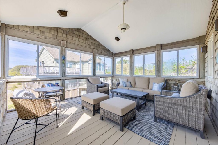 This bright enclosed porch invites you to unwind with views of the surrounding area. The wicker seating and coastal-blue accents create a breezy, relaxed vibe—perfect for morning coffee or evening conversations with loved ones.