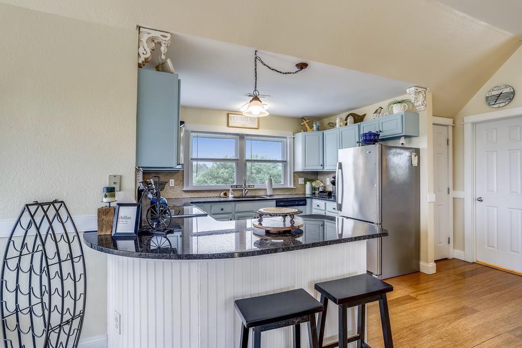 Your gourmet kitchen features granite countertops, stainless appliances, and a breakfast bar—perfect for preparing family meals or enjoying morning coffee with garden views through the windows.