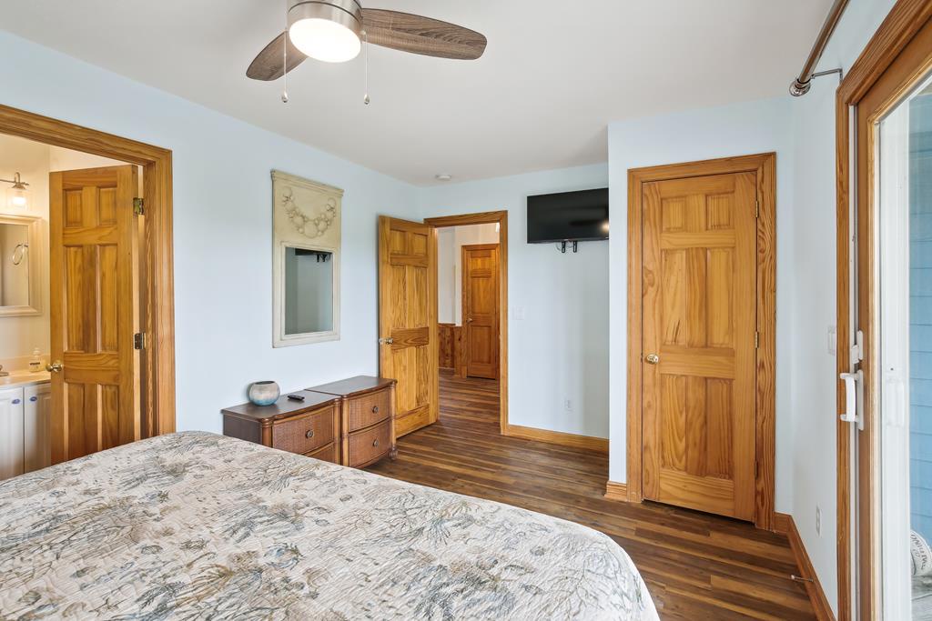Your restful bedroom features a ceiling fan for comfort, flat-screen TV for entertainment, and warm wood accents throughout. The ensuite bath and closet ensure convenience during your stay.