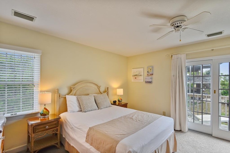 Relax in your bright, airy bedroom with soft yellow walls, a plush queen bed, and balcony doors that open to your private outdoor retreat.