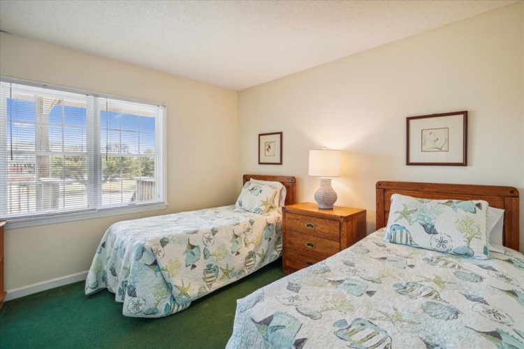 Drift into peaceful sleep in this cozy twin bedroom, where morning light filters through the blinds and beachy bedding reminds you that vacation is just beginning.