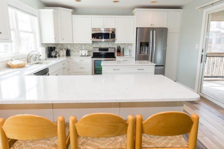 Your fully-equipped kitchen invites you to whip up meals at your leisure, with modern stainless appliances, pristine white cabinetry, and a spacious island for gathering—all bathed in soft natural light.