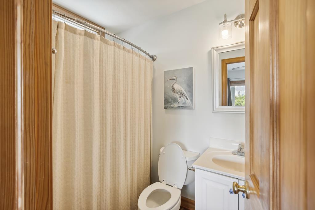 Your private bathroom offers a clean, serene space with a tub-shower combo, well-lit vanity, and coastal-inspired artwork, creating a peaceful retreat after a day of exploring.