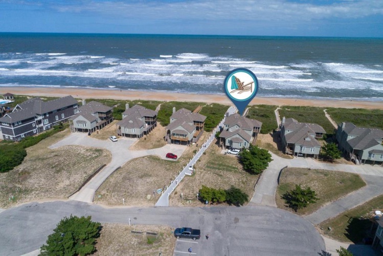 Aerial view of a beachfront property community with direct ocean access, located steps from the sandy shore and rolling waves along a scenic coastal stretch.
