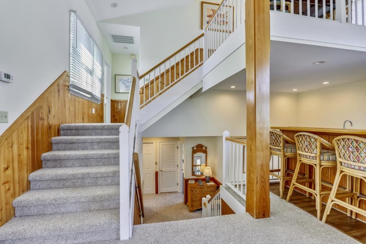 Bright, open living space with a charming staircase, cozy nooks, and bar seating perfect for gathering. Your vacation home awaits—feel right at home.