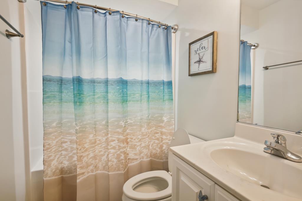 Your private bathroom features coastal charm with fresh towels, a tub/shower combo, and beach-inspired decor that brings the ocean indoors.