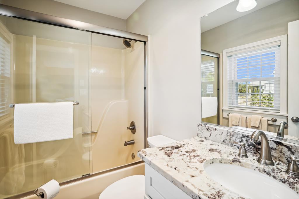 Freshen up in your sleek, modern bathroom with a spacious shower, elegant granite countertops, and plenty of natural light streaming through the window.