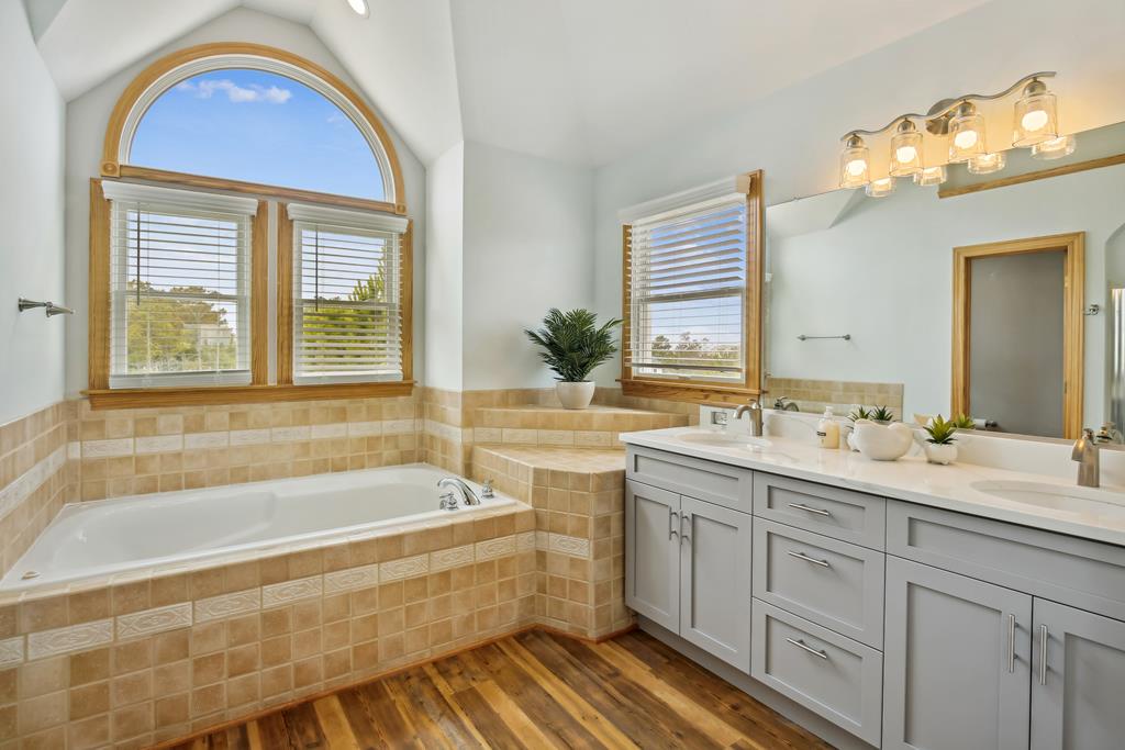 You'll love unwinding in this bright bathroom with its soaking tub, elegant tile work, and stunning natural light streaming through the arched window.