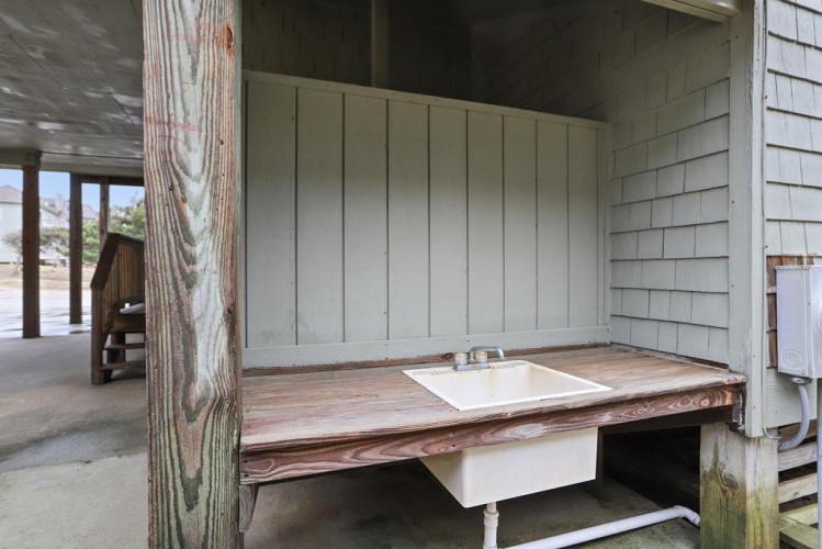 This charming outdoor utility sink sits on a rustic wooden deck, offering a practical spot to rinse off sandy feet or wash dishes after a day of adventure.