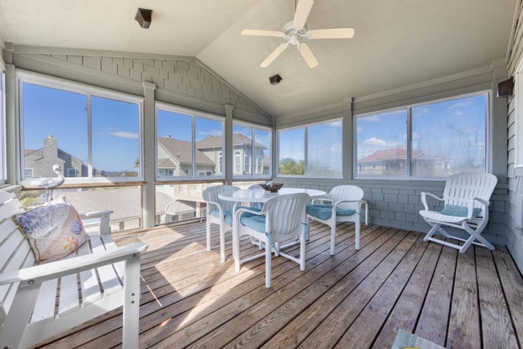 Relax in your screened porch with ceiling fan, white coastal furniture, and sweeping views—perfect for morning coffee or lazy afternoons.