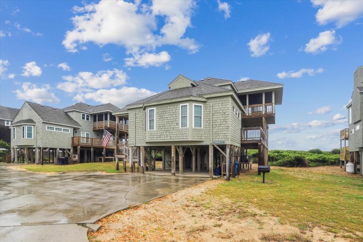 Elevated coastal home with multiple balconies featuring views of the surrounding natural landscape. The property is located in a peaceful beach neighborhood with easy access to nearby coastal areas.