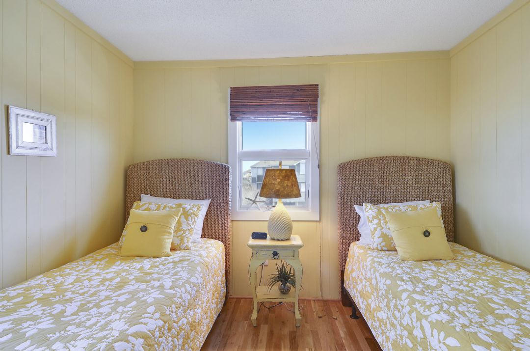 Sink into these twin beds with their cheery yellow linens and woven headboards. Wake to soft light through the window as you plan your day's adventures in this cozy, sunlit retreat.