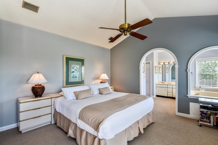 Unwind in your spacious bedroom, where vaulted ceilings and a ceiling fan keep you cool while soft lighting and coastal touches create a serene retreat after a day of adventure.